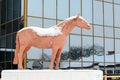 Snow-covered sculpture of horse in city park against backdrop of a glass facade Royalty Free Stock Photo