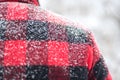 Snow covered shoulders of man in red plaid