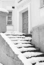 Snow-covered stone staircase of an old grey apartment building with closed door. Royalty Free Stock Photo