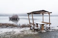 Snow covered table and benches in an empty public cafe by the lake Royalty Free Stock Photo