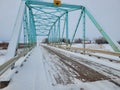 Snow covered teal colored bridge