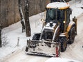 Snow-covered tractor lifting fresh snow during winter storm cleanup Royalty Free Stock Photo