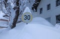 A snow-covered traffic sign with speed limit 30 in winter