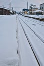 Snow-covered train tracks and platforms stretch through a small town during winter. Royalty Free Stock Photo