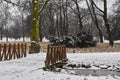 Snow-covered trees, bushes and bridge over small stream in city park in the morning. Royalty Free Stock Photo