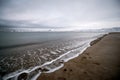 Snow-covered, white coast of the Arctic ocean, with lapping waves on large rocks