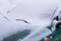 Snow-covered windshield and the side window of the car in a snowstorm