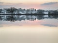 Snow covered Winter countryside sunrise landscape reflected in s