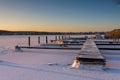 Snow-covered winter landscape with a frozen lake and boat dock at sunset Royalty Free Stock Photo