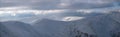 Snow covered winter mountains last evening sunlight. Magnificent windy dusk on tops above picturesque alpine ski resort