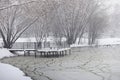 Snow-covered winter park and benches. Park and pier for feeding ducks and pigeons. The first snow covered the autumn park Royalty Free Stock Photo