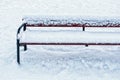 Snow covered wooden bench in winter park on fluffy white snow background Royalty Free Stock Photo