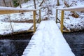 Snow-covered wooden bridge over a small river. Royalty Free Stock Photo