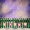 Snow-covered wooden fence with hanging on it with paper hearts Royalty Free Stock Photo