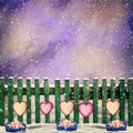 Snow-covered wooden fence with hanging on it with paper hearts a Royalty Free Stock Photo