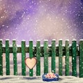 Snow-covered wooden fence with a paper heart and a gift Royalty Free Stock Photo