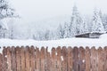 Snow covered wooden fence and snowy trees on background Royalty Free Stock Photo