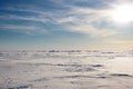 Snow desert and blue winter sky. Mountains on the horizon