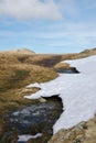 Snow drift and boggy stream in marsh moorland