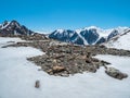 Snow drifts on a mountain slope. Atmospheric mountain landscape with glacier on rocky hill. Awesome scenery with stony pass with Royalty Free Stock Photo