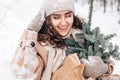 A young woman is sitting in the snow with her eyes closed , laughing and holding a nobilis Royalty Free Stock Photo