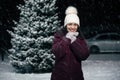 Beautiful woman smiling a toothy smile looking at camera, standing against a snow-covered fir-tree on a snowy night Royalty Free Stock Photo