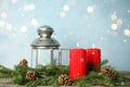 Snow falling on burning candles and Christmas lantern against blurred festive lights