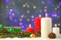 Snow falling on burning candles and festive decor against blurred Christmas lights, space for text