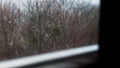 Snow falls. Winter landscape through the window in the house.