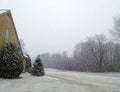 Snow flurries covering home,yard,road and bare trees Royalty Free Stock Photo