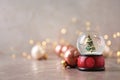 Snow globe with Christmas tree and decorations on marble table against festive lights