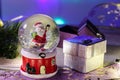 Snow globe with Santa inside and gift box close up on wooden table. Christmas gifts concept Royalty Free Stock Photo