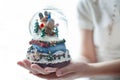 Snow globe with a snowman in the hands of a girl. White background