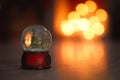 Snow globe on wooden table against blurred background. Bokeh effect Royalty Free Stock Photo