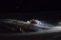 A snow groomer compacting ski runs at night