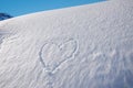 Snow heap with carved love heart, blue sky. mountain landscape