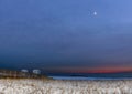 Snow and ice covering the Long Beach boardwalk and beach ramps, with the moon rising in the dusk sky