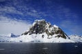 The snow on the iceberg is about to melt and most of the rocks can be seen.