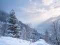 Snow in the italian Alps. Beautiful view of idyllic village in snowy forest and snowcapped mountain peaks. Piedmont, Italy Royalty Free Stock Photo