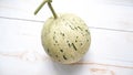 single snow leopard melon (dalmatian melon) on a white wooden table