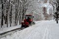 Snow machine, red tractor cleans the snow from the snow in the background of the forest.