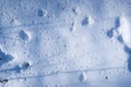 Snow macro with holes after thaw and animal trace, winter forest sundawn and sun flare, long deep shadows of tree twigs Royalty Free Stock Photo