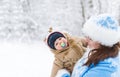 Snow maiden and baby boy embracing in a winter park amoung trees branches.