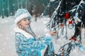 Snow Maiden. portrait of a little girl in winter in elegant festive costume. child decorates the Christmas tree in the forest.