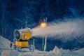 Snow making machine on the hill working on the ski run in evening Royalty Free Stock Photo