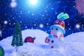 Snow Man with Christmas balls on snow over fir-tree, night sky and moon. Shallow depth of field. Christmas background Royalty Free Stock Photo