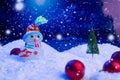 Snow Man with Christmas balls on snow over fir-tree, night sky and moon. Shallow depth of field. Christmas background Royalty Free Stock Photo