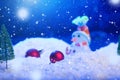 Snow Man with Christmas balls on snow over fir-tree, night sky and moon. Shallow depth of field. Christmas background Royalty Free Stock Photo