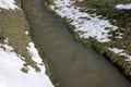 Snow is melting and thawing into canal with flowing water