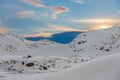 Snow mobile with metal trailer parked on the rocky side of a small snow covered mountain in the Arctic Royalty Free Stock Photo